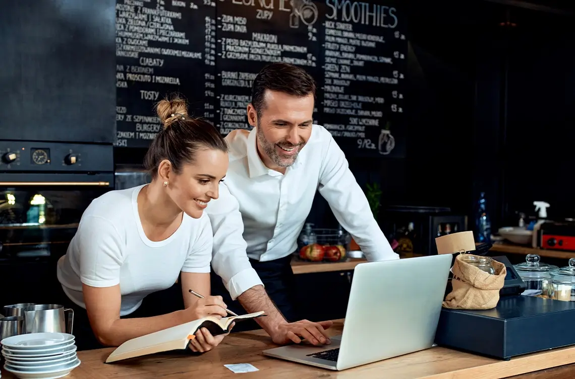 A restaurant owner and a marketer working together to set up the automated phone menu for their restaurant.