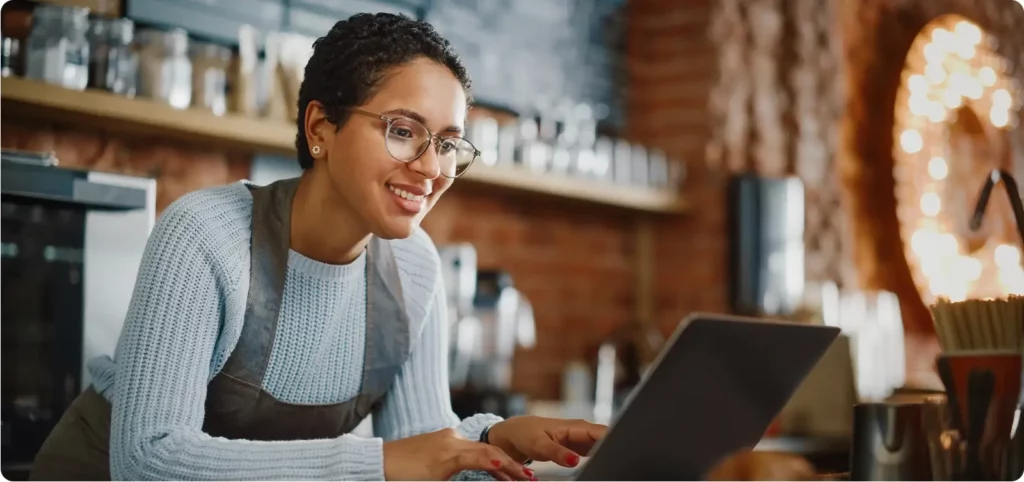 A restaurant owner works on her laptop before opening to make better, more effective decisions about her restaurant using AI.