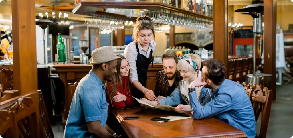 A waitress at a restaurant educates the patrons about the new text ordering for restaurants that they offer while they sit at their table.