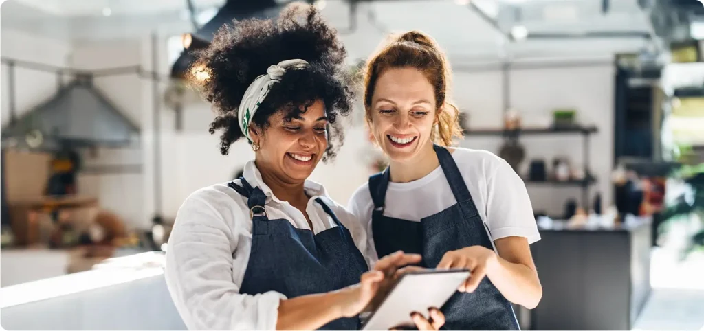 Two women review information on their tablet to help them improve their restaurant efficiency.